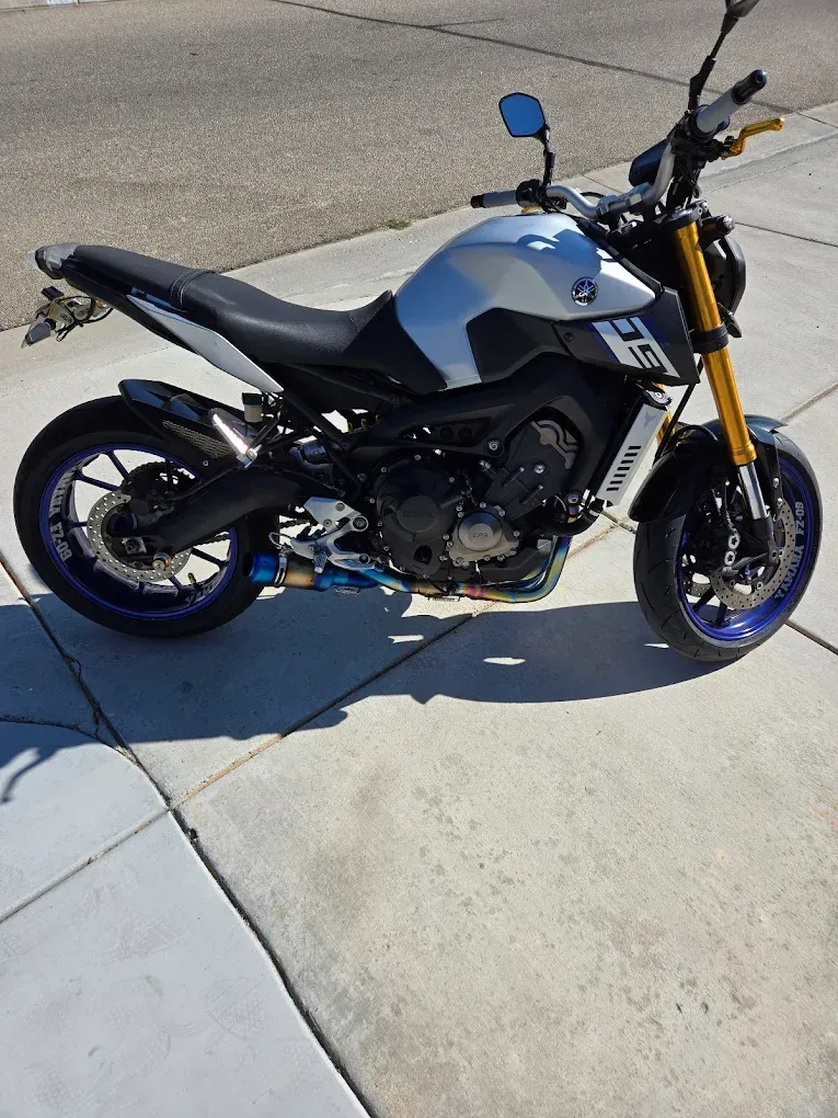 Blue and black Yamaha motorcycle parked on a concrete driveway in sunlight
